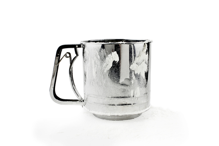 Metal flour sifter with flour dusted on the side and beneath isolated over a white background. の写真素材