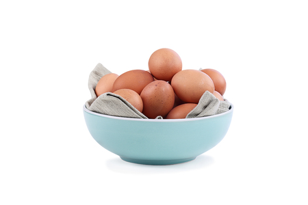 Isolated farm fresh organic brown chicken eggs from free range chickens in a blue bowl over a white background with light shadow.の写真素材