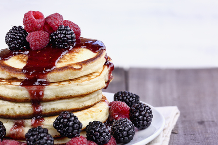 Delicious homemade golden pancakes with fresh blackberries, raspberries, and raspberry syrup. Extreme shallow depth of field.の写真素材