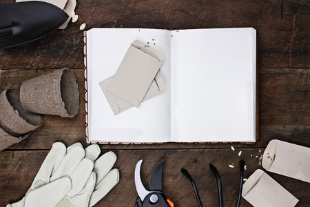Gardening journal surrounded with tools, tomato seeds and flower pots on a rustic wooden table. Image shot from above in flat lay style.の写真素材