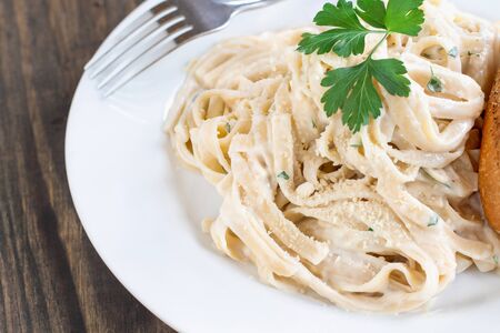 Plate of fettucini alfredo with fresh parsley and a slice of french bread. Top view.の写真素材