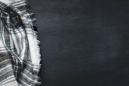 Warm woven black, white and gray blanket crumpled over a black wooden background. Shot from above top view with free space for text for background. の写真素材