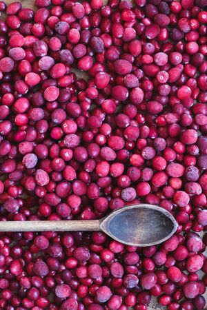 Background of frozen preserved fresh cranberries with vintage wooden spoon. Image shot from top view.の写真素材