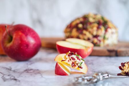 Cranberry spread made with goat cheese, dried cranberries, walnuts, and chives. Served with fresh sliced apples over a marble table. Selective focus with blurred background.の写真素材