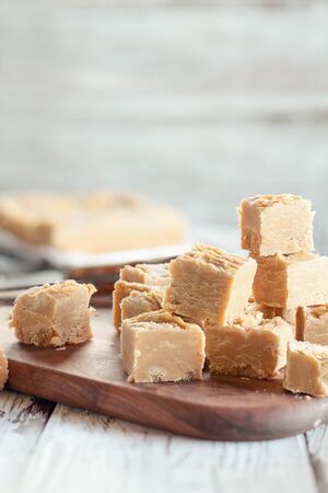 Squares of delicious, homemade peanut butter fudge over a rustic wood table. Selective focus on candy in the foreground with blurred background. の写真素材
