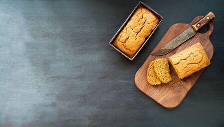 Two freshly baked homemade pumpkin bread loaves with knife over dark background. Image shot from top view, flatlay.の写真素材