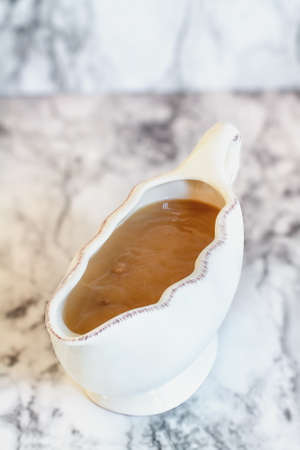 Homemade turkey gravy in a gravy boat or sauceboat ready for Thanksgiving Day. Image shot from high angle view.の写真素材