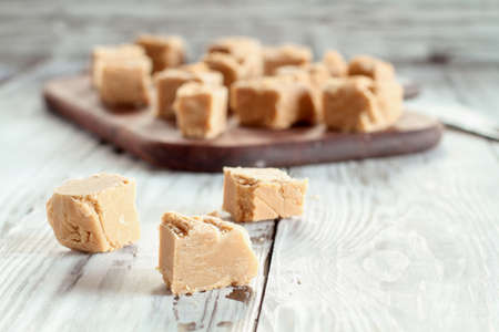 Squares of delicious, homemade peanut butter fudge over a rustic wood table. Selective focus on candy in the foreground with blurred background.の写真素材