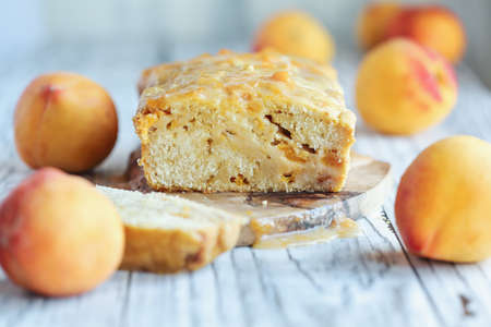 Delicious homemade peach sweet bread with frosting and fresh peaches. Selective focus with blurred...