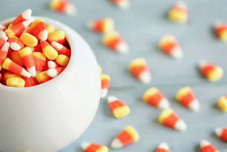 Halloween holiday candy corn in a white bowl over a blue wooden background for Trick or Treat.の写真素材