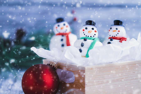 Three iced Christmas Snowman cupcakes with carrot nose, santa hat, and scarf in a box. Selective focus with blurred foreground and background.の写真素材