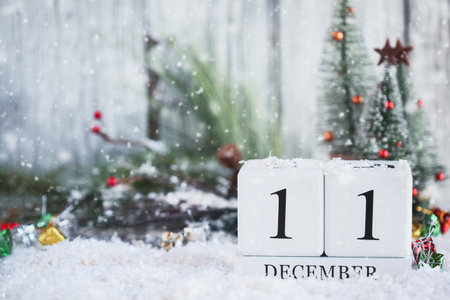 White wood calendar blocks with the date December 11th and Christmas decorations with snow. Selective focus with blurred background.の写真素材
