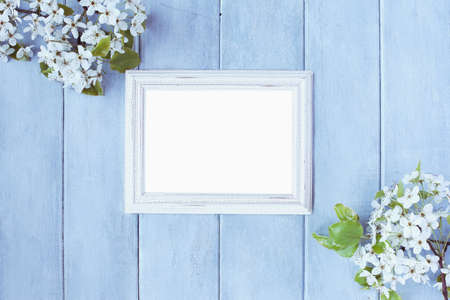 Blank horizontal empty picture frame over blue rustic background with spring flowers.