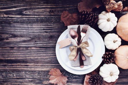 A holiday place setting with plate, napkin, on a Thanksgiving Day decorated table shot from flat lay or top view position. Silverware tied with gold ribbon bow.の写真素材