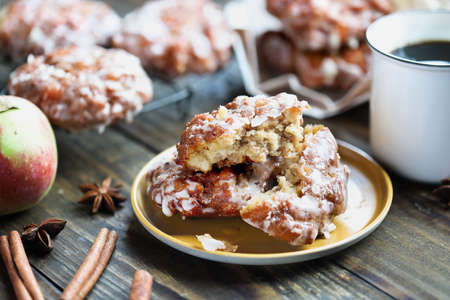 Glazed apple fritters and hot coffee with fresh apples, cinnamon bark and anise. Selective focus with blurred background and foreground.の写真素材