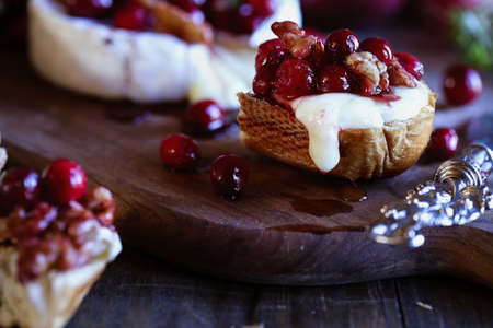 Toasted bread served with baked Camembert Brie cheese and a cranberry, honey, balsamic vinegar and nut relish. Selective focus with extreme blurred foreground and background.の写真素材