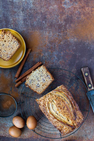 Top view of fresh homemade banana bread cooling on a baker's rack with ingredients nearby. Flatlay with copy space. Selective focus on loaf with blurred backgroundの写真素材