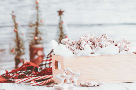 Homemade white chocolate or yogurt covered pretzels with pieces of crushed candy cane. Selective focus with blurred foreground and background. Heart shaped canes on the table.の写真素材