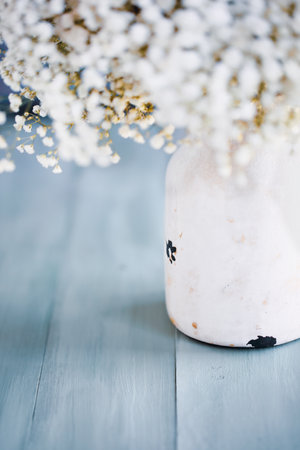 Bouquet of Baby's Breath flowers in a rustic white vase over a blue table for Mother's Day. Selective focus with extreme blurred background and foreground.の写真素材