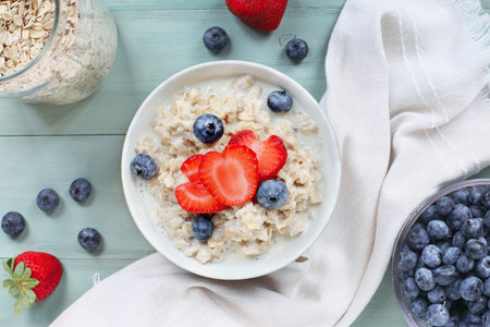 Homemade hot bowl of creamy whole grain oatmeal with fresh strawberries and blueberries. Image shot from table top view.の写真素材