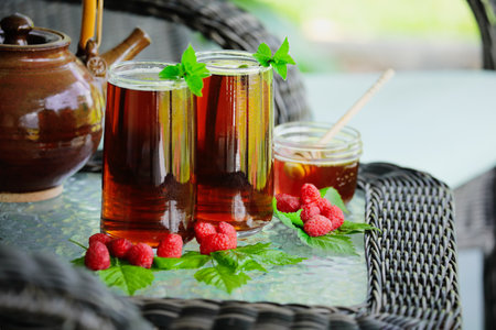 Herbal tea with raspberries and mint leaves used as natural remedy for digestive, respiratory health and to prepare the body for labor. Selective focus on 2nd glass, blurred foreground and background..の写真素材