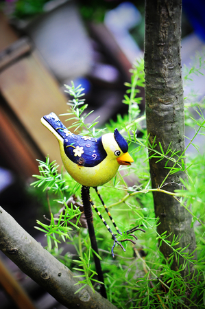 Front View of Yellow bird figurine standing in a gardenの写真素材