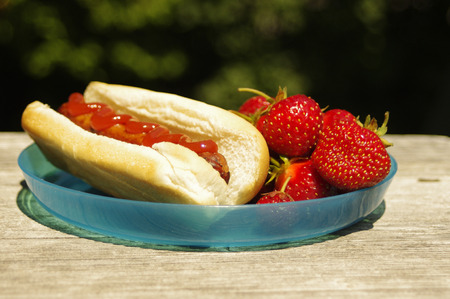 a plate with a hotdog and strawberriesの写真素材