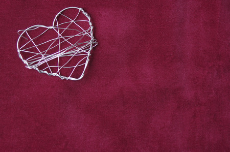 One metal wire heart on a velvet red background