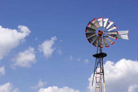 tall old metal windmill in blue skyの写真素材