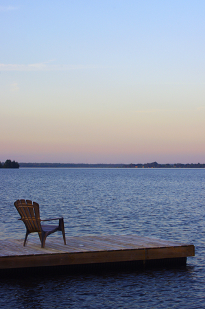 Adirondack chair on wooden dock at sunsetの写真素材