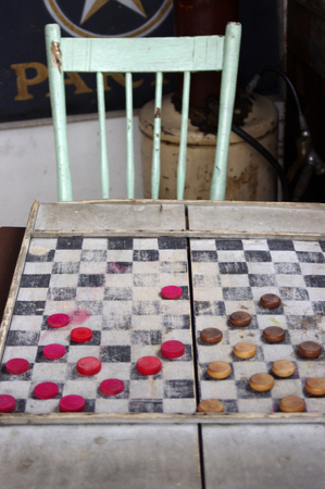Vintage wooden red and brown checkers on old board game  with old chairの写真素材