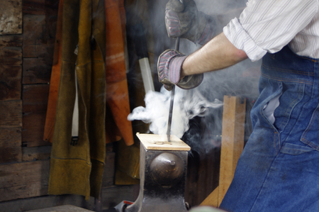 Man using vintage wood burning tools with smokeの写真素材