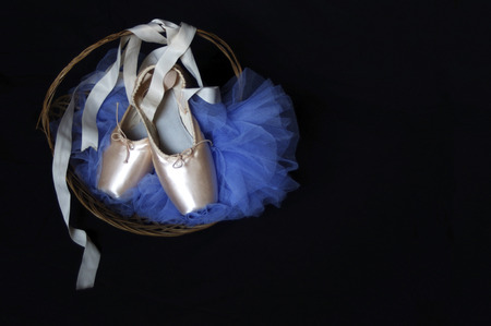 new pink Pointe ballet shoes basket with blue tutu  on black with copy spaceの写真素材