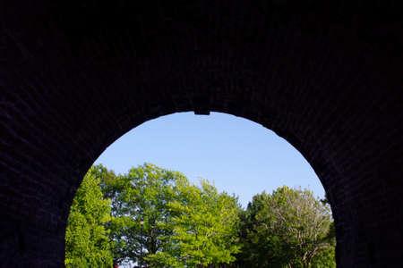 old curved tunnel entrance looking out at treesの写真素材