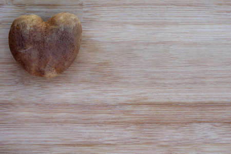 heart shaped potato on wood background with copy spaceの写真素材