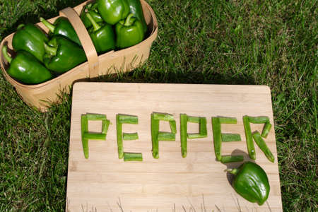 ripe green peppers with word pepper in pieces on grassの写真素材