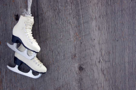 white figure skates ornament on white snow with rustic wooden background and copy spaceの写真素材