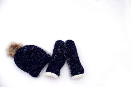 dark blue knit mittens and hat in white snow with copy spaceの写真素材