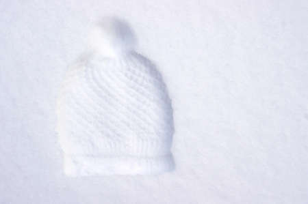 imprint of knit hat with pompom in white snow with copy space