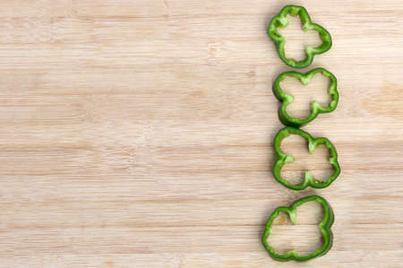 ripe green pepper ring slices on wooden background with copy space