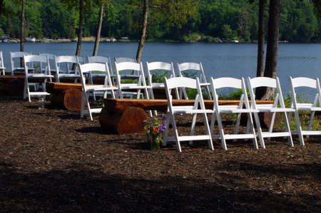 white wooden wedding chairs in rows outside in nature with waterの写真素材