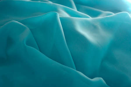 turquoise green flowing fabric background texture with copy spaceの写真素材
