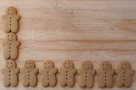 rows of cute festive gingerbread cookies on wooden table with copy spaceの写真素材