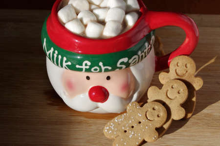 funny Santa Clause face coffee mug with hot chocolate, marshmallows, gingerbread cookies on wooden tableの写真素材