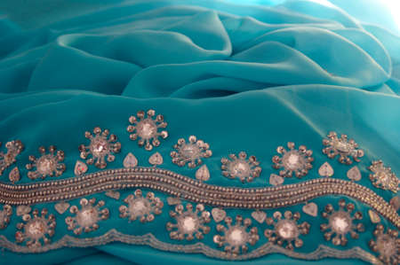flower rhinestone details on turquoise green flowing fabric background texture with copy spaceの写真素材