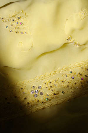 moody rhinestone details on yellow flowing fabric background texture with copy spaceの写真素材
