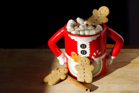 three gingerbread  smiley face cookies in a funny Mrs. Santa Clause coffee mug with hot chocolate, marshmallowsの写真素材