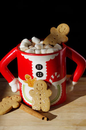 three gingerbread  smiley face cookies in a funny Mrs. Santa Clause coffee mug with hot chocolate, marshmallowsの写真素材