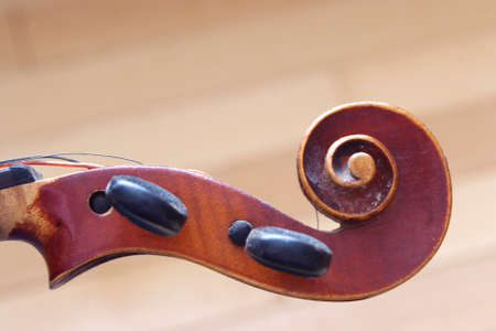 vintage brown violin head music instrument close up on light brown backgroundの写真素材