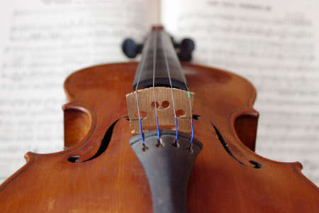 vintage brown violin music instrument on white sheet music close up